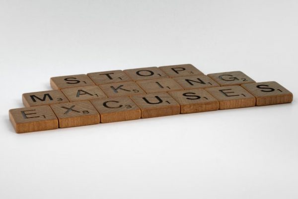 Inspirational phrase "Stop making excuses" crafted with wooden letter tiles.